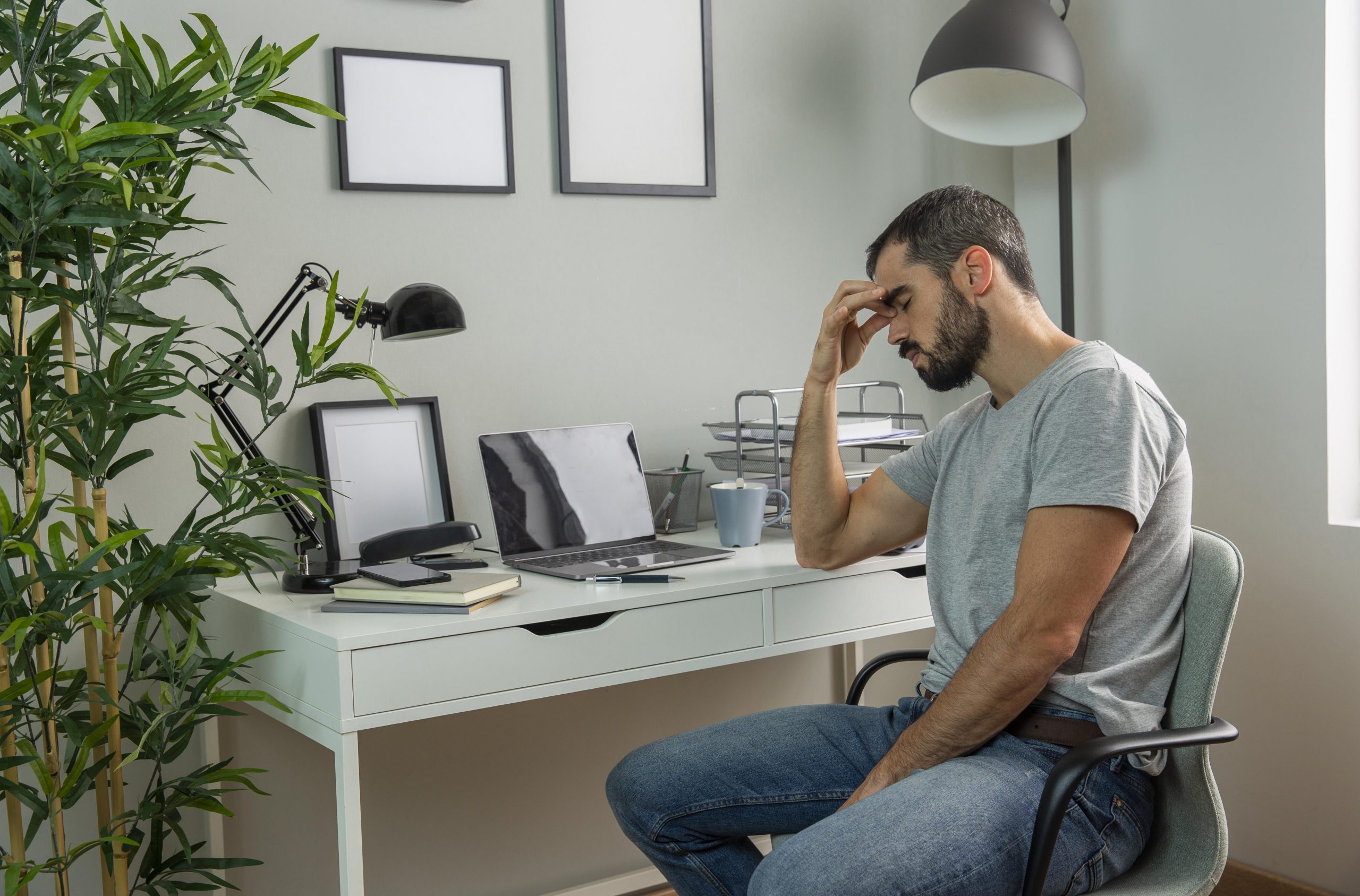 hombre cansado sentado en el escritorio de su casa scaled